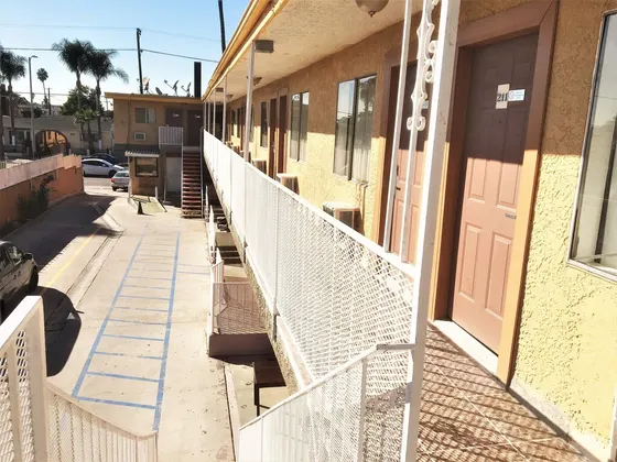 Building with a balcony, a parking lot, and a street with cars