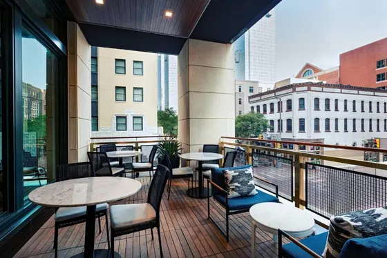 Outdoor terrace with marble-topped tables overlooking city buildings
