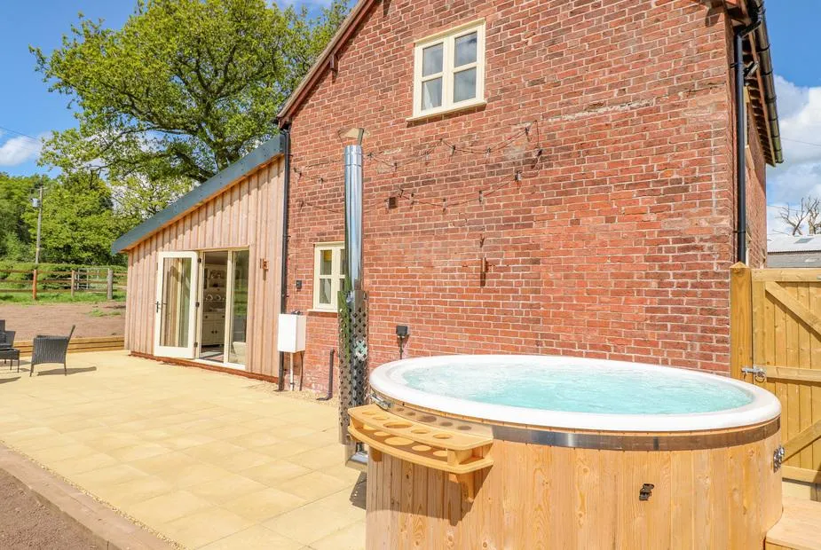 Acorn Lodge wooden hot tub beside the property with blue sky