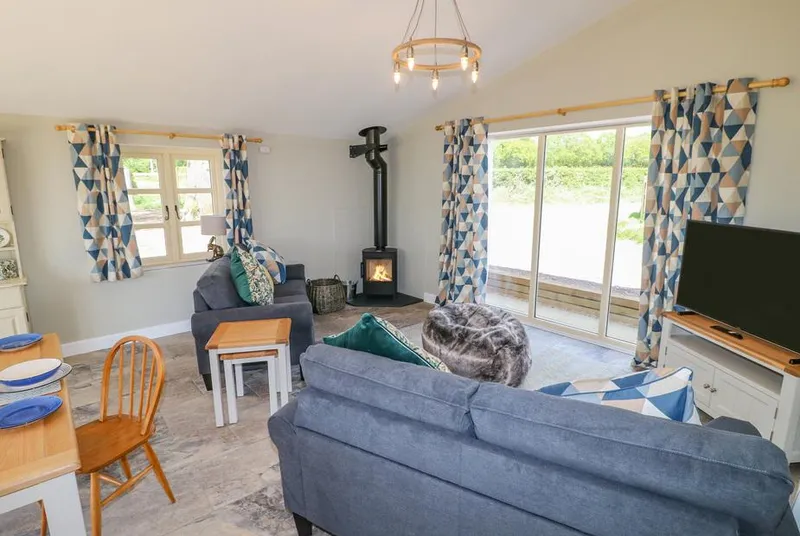 Acorn Lodge open-plan living room with lit wood burner and blue sofas