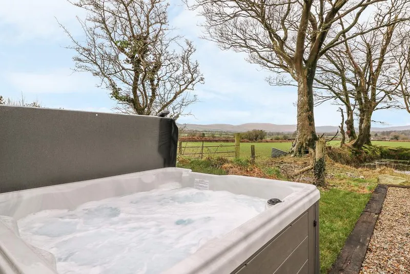 Bwthyn Lan hot tub with open countryside beyond the garden