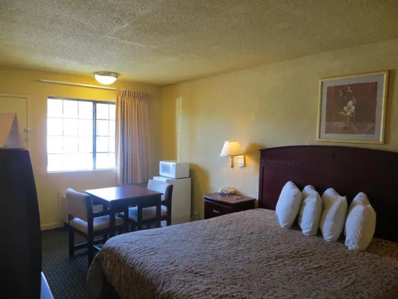 Yellow-walled room with a patterned bedspread and small table