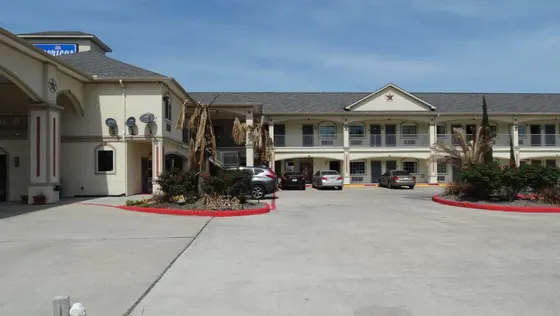 Beige two-story motel with palm trees and outdoor walkways