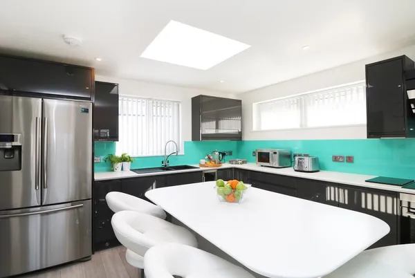 An Drowes glossy kitchen with island and stools