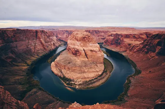 Dark river curving around a massive orange sandstone rock