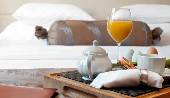 Breakfast tray with teapot, juice, and eggs on a white bed