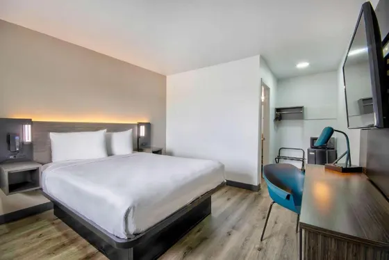 Room with a white bed, wooden desk, and blue chair