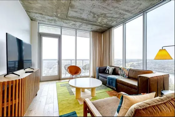 Living room with a leather sofa and floor-to-ceiling city views