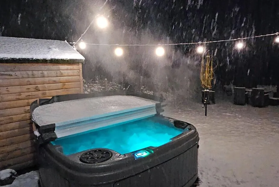 Balmore Farmhouse hot tub lit at night in the snow