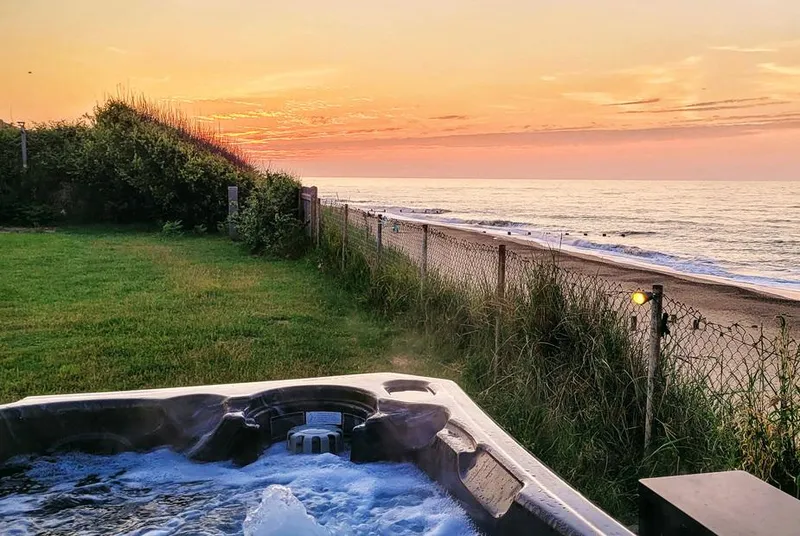 Beach Haven clifftop hot tub at sunset with sea views