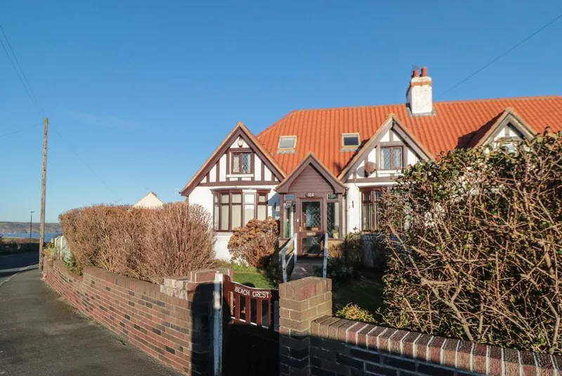 Beachcrest Tudor-style exterior under blue sky with sea views