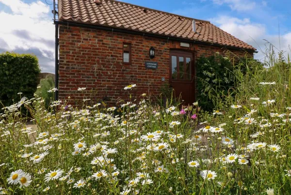 Lovesome Cottage brick barn behind wildflower meadow