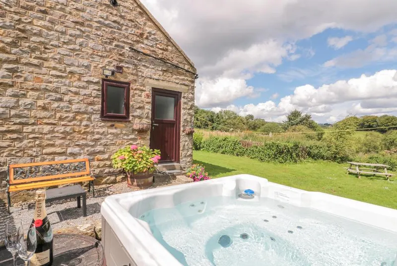 Carters hot tub beside stone cottage wall with countryside