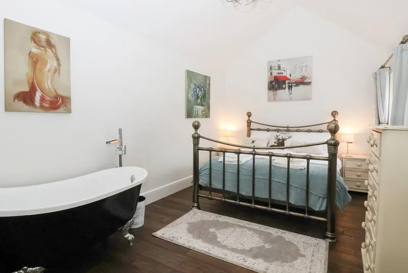 Beckside Cottage bedroom with brass bed and freestanding roll-top bath