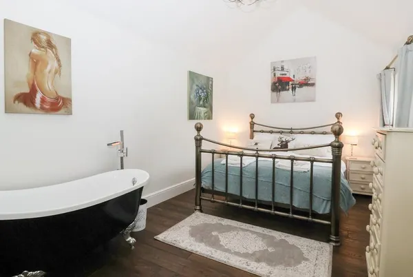 Beckside Cottage bedroom with brass bed and freestanding roll-top bath