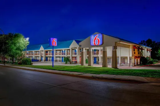Tan motel at dusk with a blue roof and Motel 6 signs