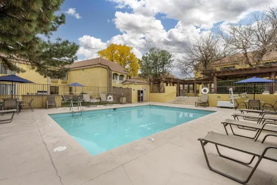 Outdoor pool with lounge chairs and yellow stucco buildings