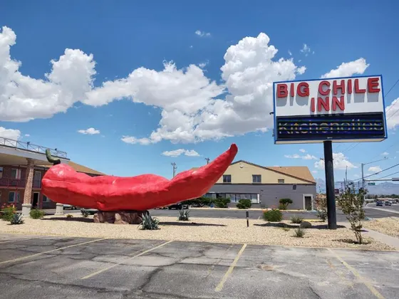 Giant red chile pepper sculpture beside a Big Chile Inn sign