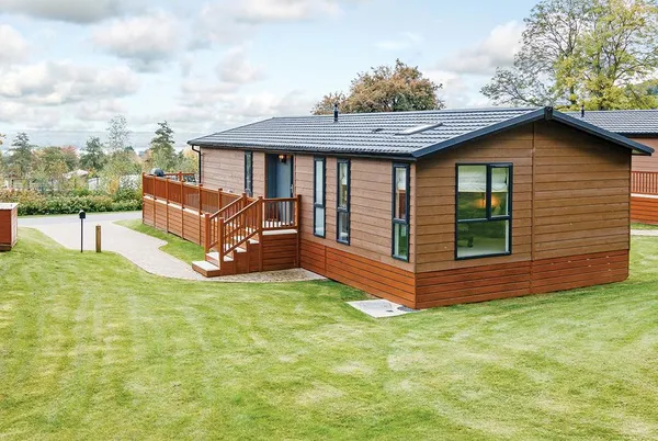 Brunel Premier Elegance Lodge 3 timber-clad lodge exterior with deck and blue sky