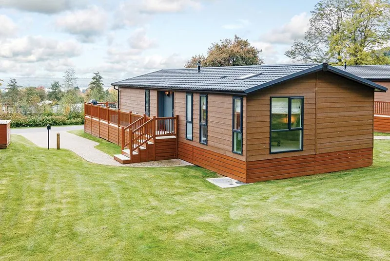 Brunel Premier Elegance Lodge 3 timber-clad lodge exterior with deck and blue sky