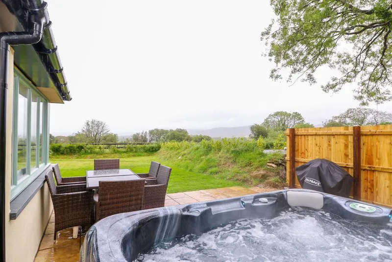 Bwthyn Eisteddfa Fach hot tub beside the patio table and rural view