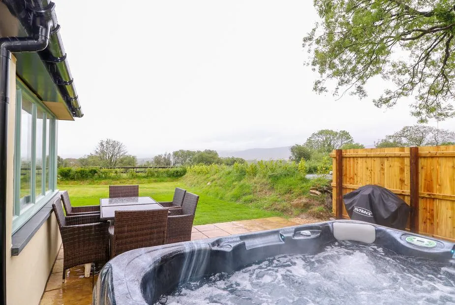 Bwthyn Eisteddfa Fach hot tub beside the patio table and rural view