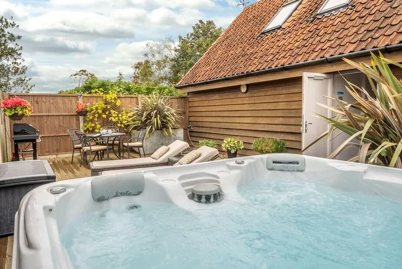 Cartshed Lodge Hoveton hot tub on decked area in garden setting