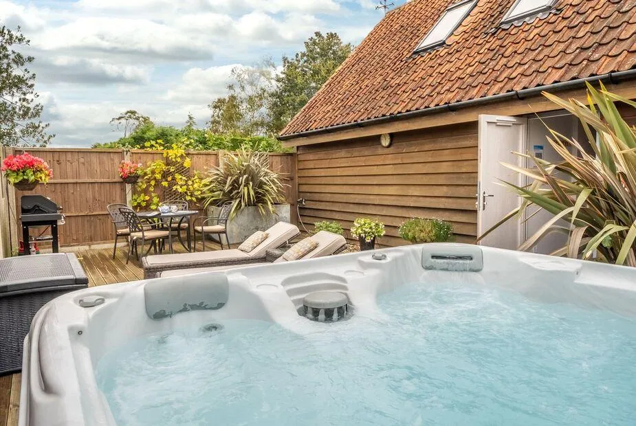 Cartshed Lodge Hoveton hot tub on decked area in garden setting