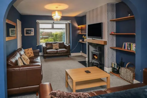 Castle View living room with deep blue walls and lit wood burner