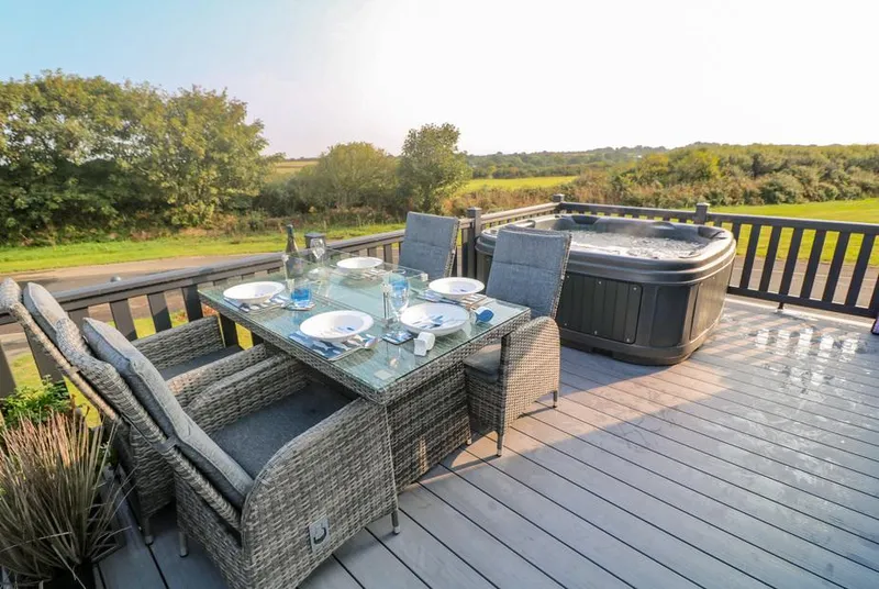 Chantry Lodge deck dining area with hot tub and coastal view