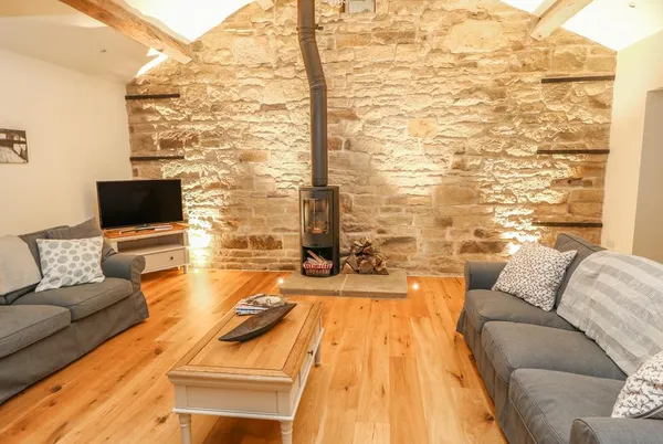 Morgan's Barn wood burner on exposed stone wall with sofas