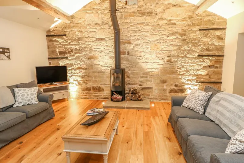 Morgan's Barn wood burner on exposed stone wall with sofas
