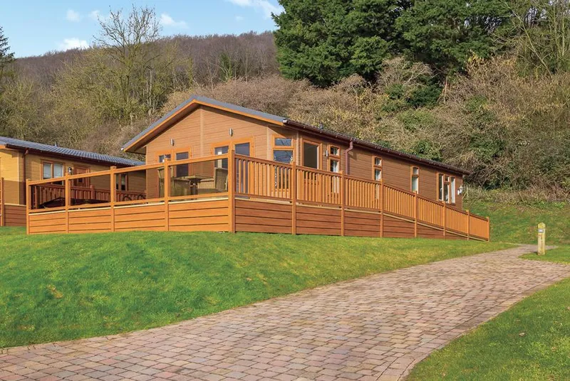 Cheddar Lodge Premier WF lodge exterior with wooded Cheddar hillside backdrop
