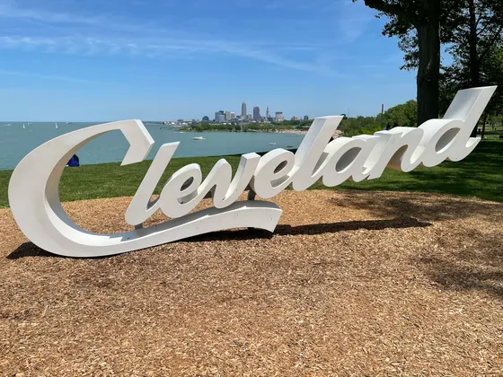 White Cleveland script sign with lake and skyline