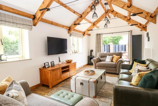 Cobblers Barn living room with vaulted ceiling, beams, and wood burner