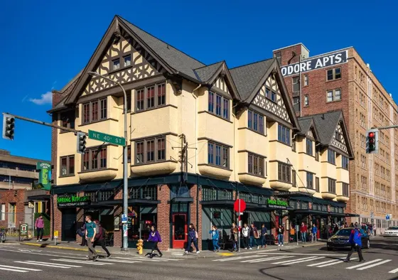 Building on the corner of a street with people crossing the street