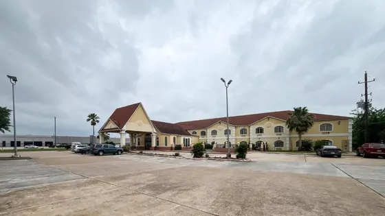 Cream hotel with a red roof and a large parking lot