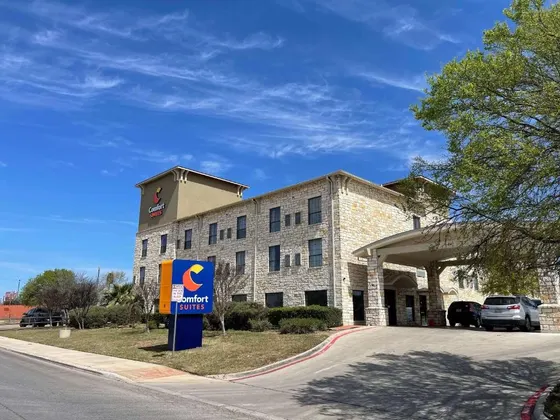 Three-story stone hotel with a blue sign and covered driveway