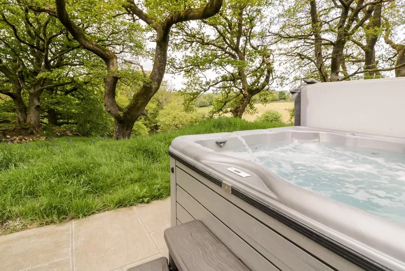 Conwy Pod bubbling hot tub beside the pod in the trees