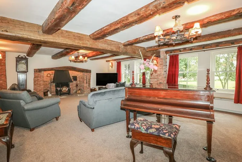 Copmanthorpe Hall living room with fireplace, grand piano and exposed beams