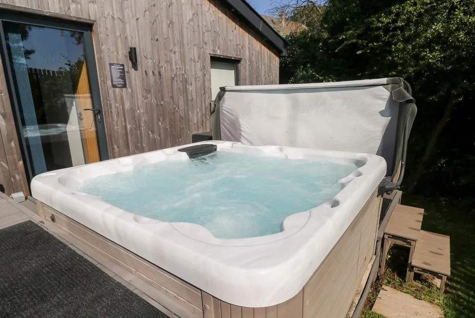 Cornerstones Brython bubbling hot tub with cedar cabin wall behind