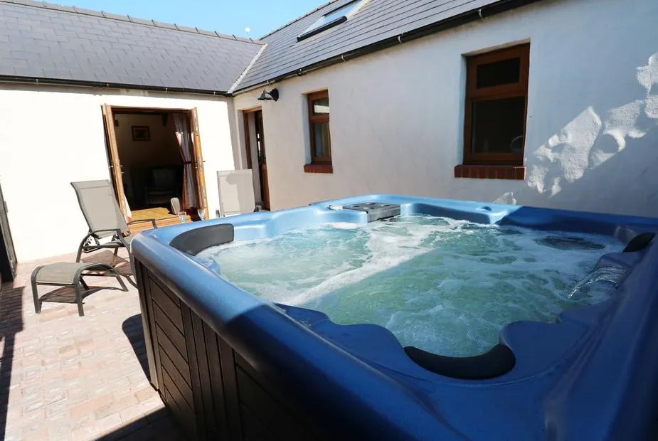 Stable Cottage hot tub beside the whitewashed cottage wall