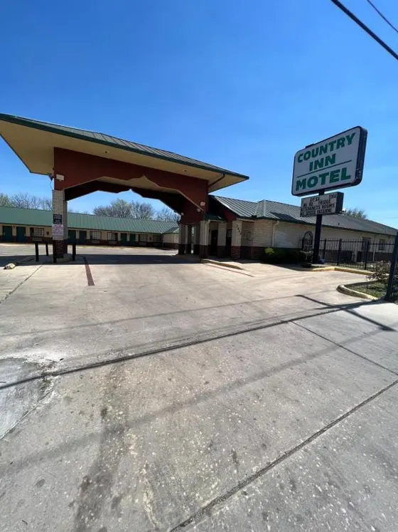 Country Inn Motel sign and green-roofed porte-cochere under blue sky