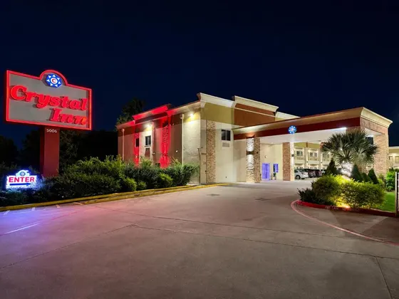 Beige hotel with a glowing red Crystal Inn sign at night