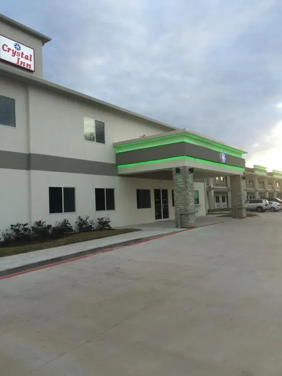Beige hotel with a green-lit canopy and Crystal Inn sign
