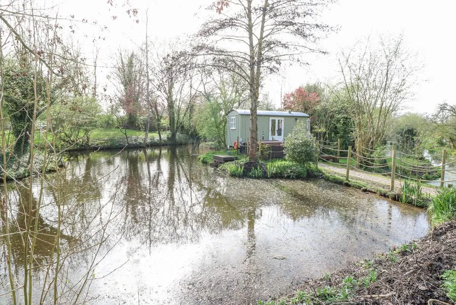 Damsel Shepherds Hut across the fishing lake with water reflection