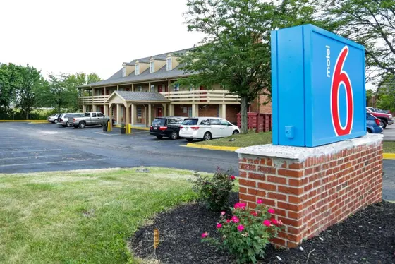 Blue Motel 6 sign in front of a tan two-story motel