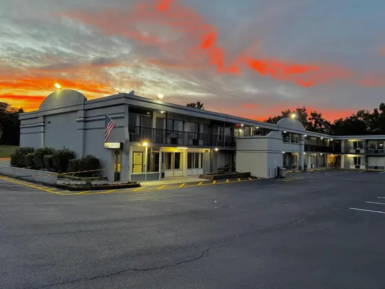 Gray motel with lights on under an orange sunset sky