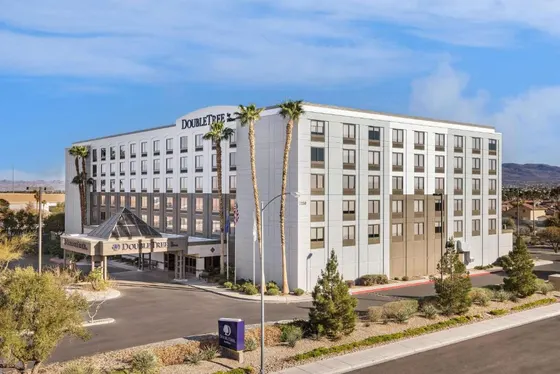 Large white building with palm trees in front of a street