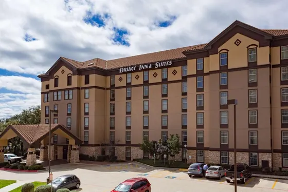 Tan hotel with a red tile roof, Drury sign, and parking lot